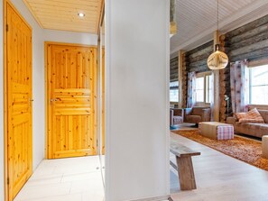 A wooden door, a bench, and a sofa in a room with a high ceiling and large windows. - Nilikuru d9 by Interhome (Inari)
