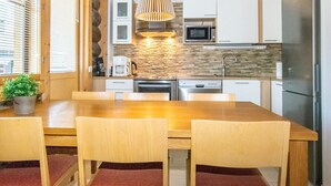 A modern kitchen with a wooden table and chairs, a built-in microwave, and a stainless steel refrigerator.
