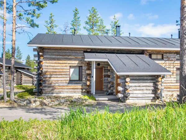 Een vakantiehuisje van hout met schuin dak, een voordeur en een klein terras.