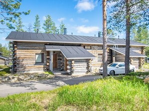 A log cabin with a metal roof, a front porch, and a car parked in front. - Nilikuru e 12 by Interhome (Inari)