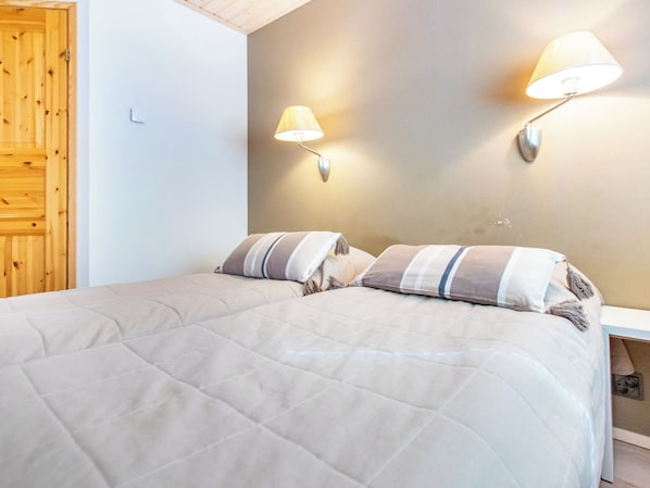 Een slaapkamer met een bed, twee wandlampen en een houten deur.
