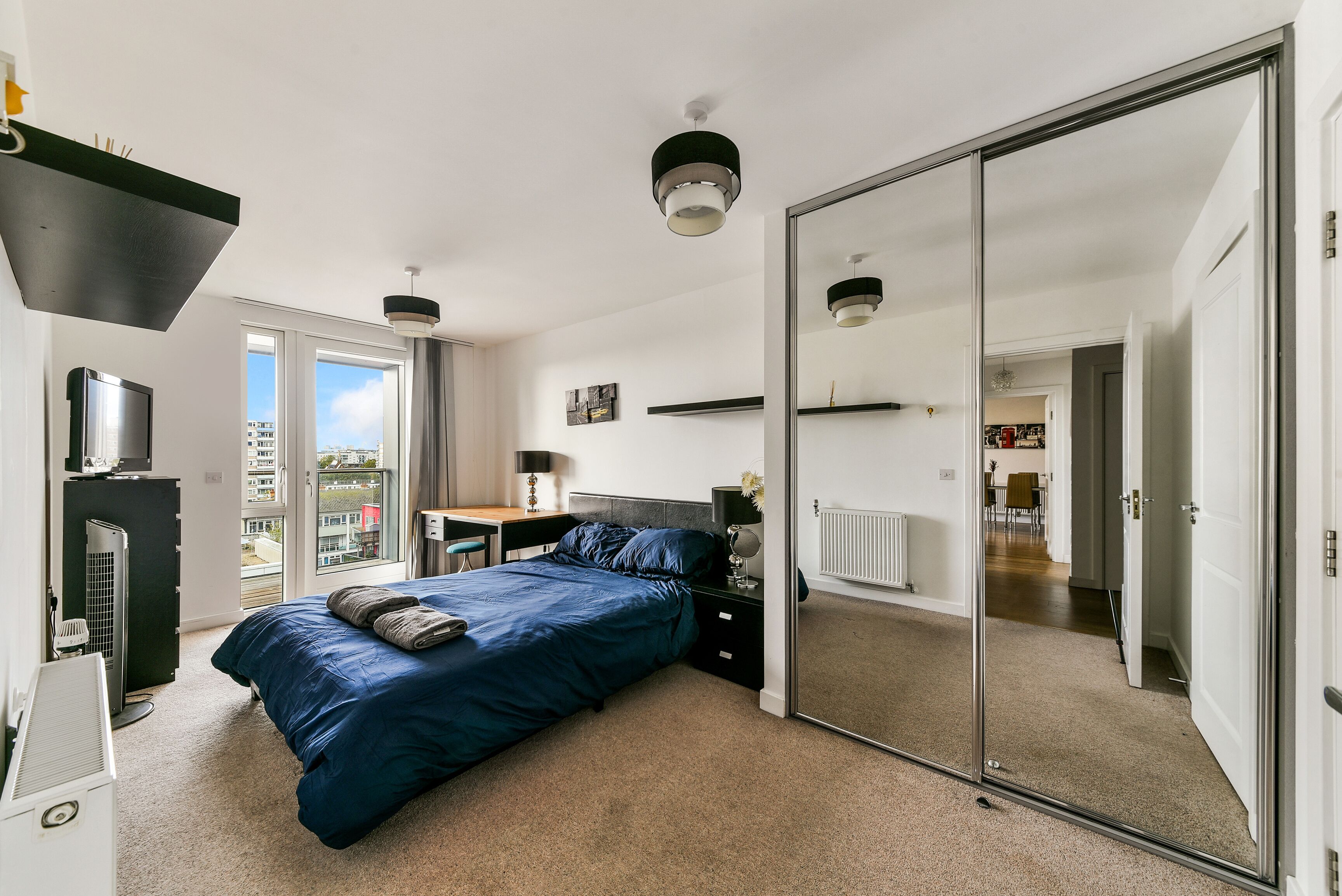Une chambre moderne avec un grand lit, un bureau et une porte de placard coulissante.