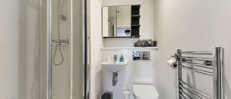 A modern bathroom with a glass shower enclosure, a white sink, a toilet, and a towel rack.
