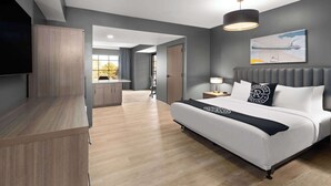A modern hotel room with a large bed, a TV, a desk, and a view of the outdoors. - Riverbend Hotel and Suites, Trademark Collection by Wyndham (Ashtabula)