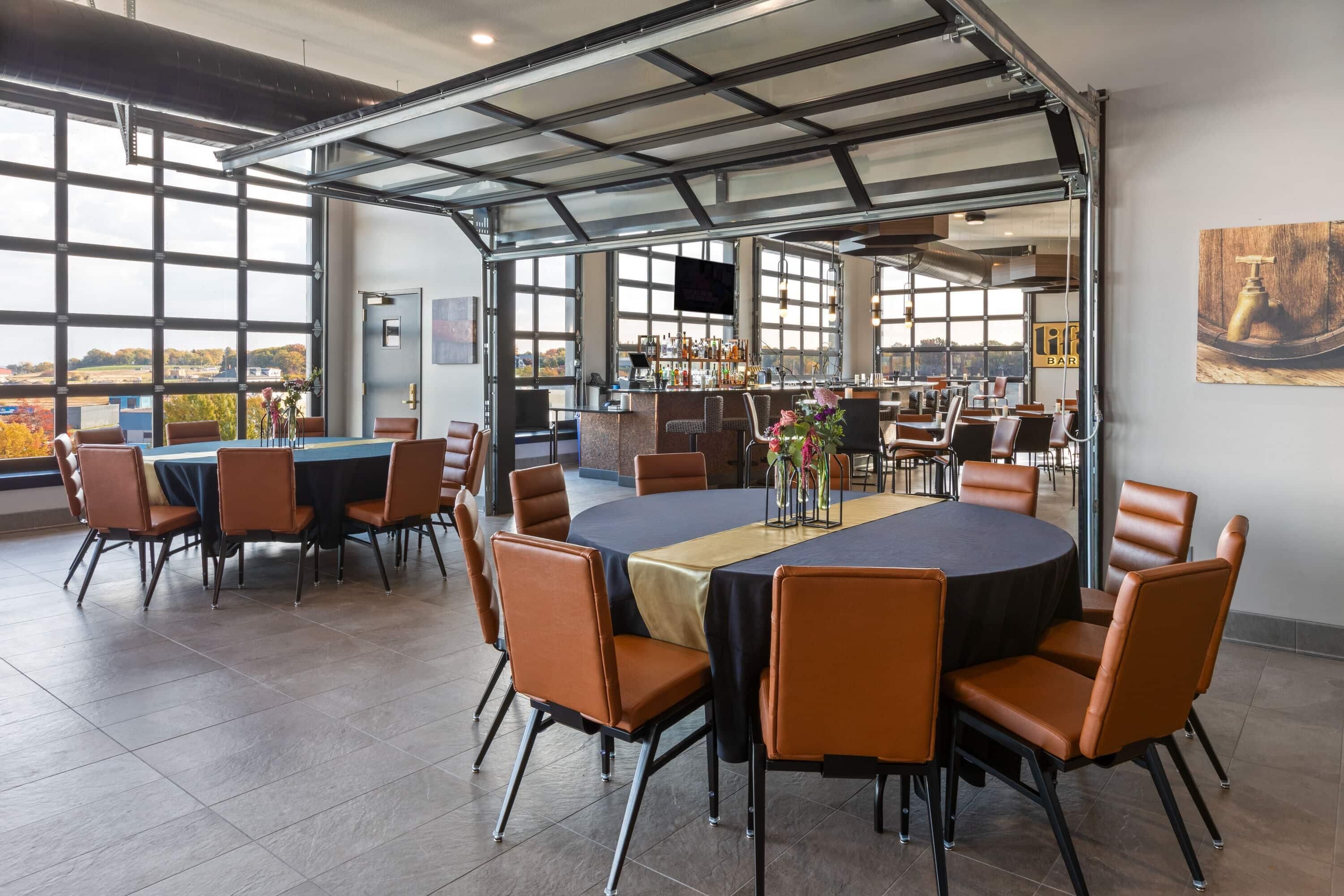 A spacious indoor dining area with large windows, a bar, and a view of the outside.