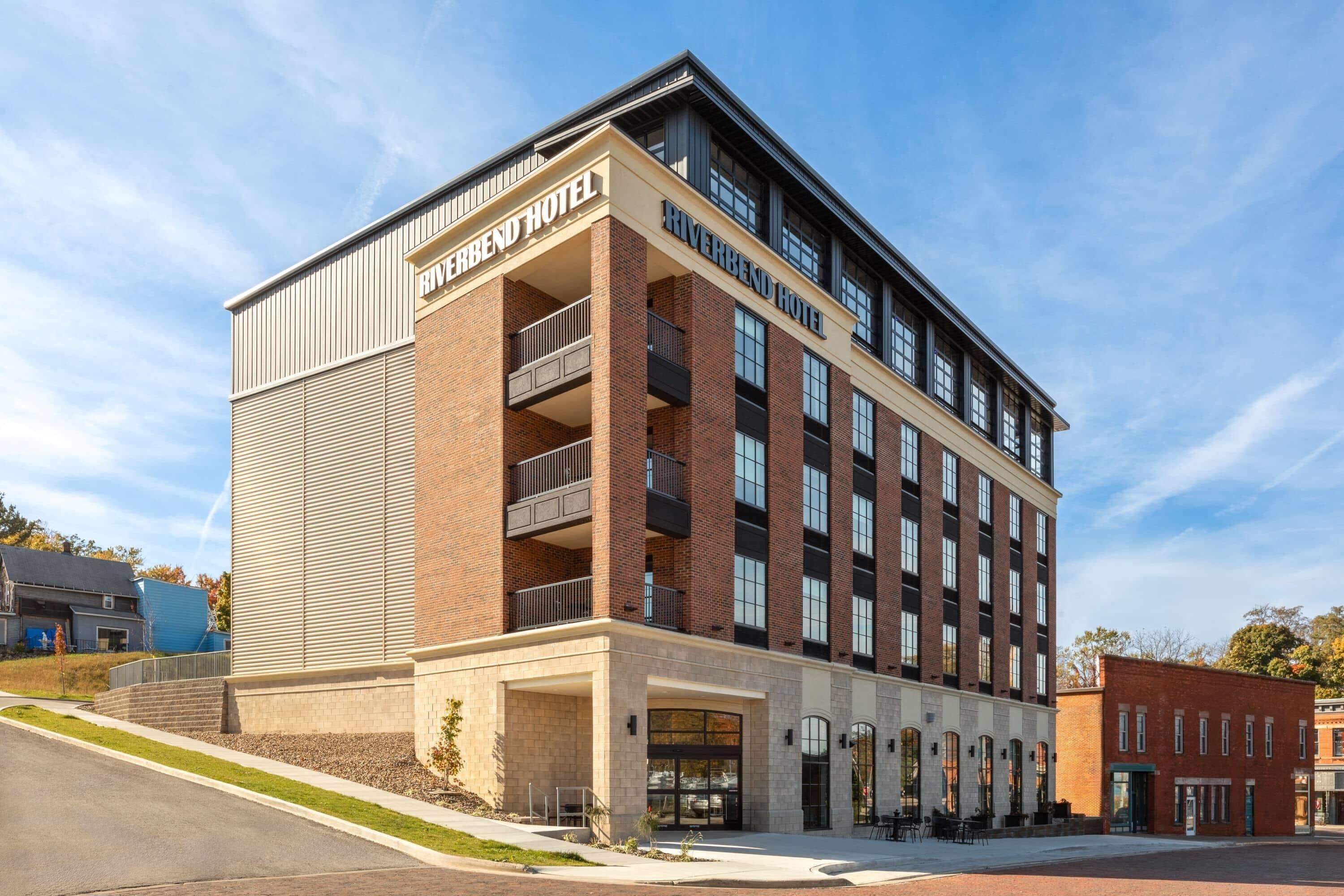 A multi-story hotel with a prominent 'Riverbend Hotel' sign, a brick facade, and a flat roof.