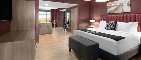 Une chambre d’hôtel moderne dotée d’un grand lit, d’une télévision, d’un bureau et offrant une vue sur le paysage urbain.