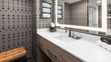 A bathroom with a vanity, mirror, towel rack, and bench.
