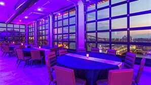 A restaurant with large windows, round tables, and chairs. - Riverbend Hotel and Suites, Trademark Collection by Wyndham (Ashtabula)