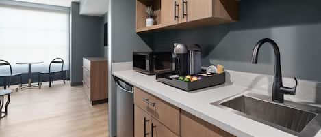 A modern kitchen with wooden cabinets, a built-in microwave, a coffee maker, and a sink.