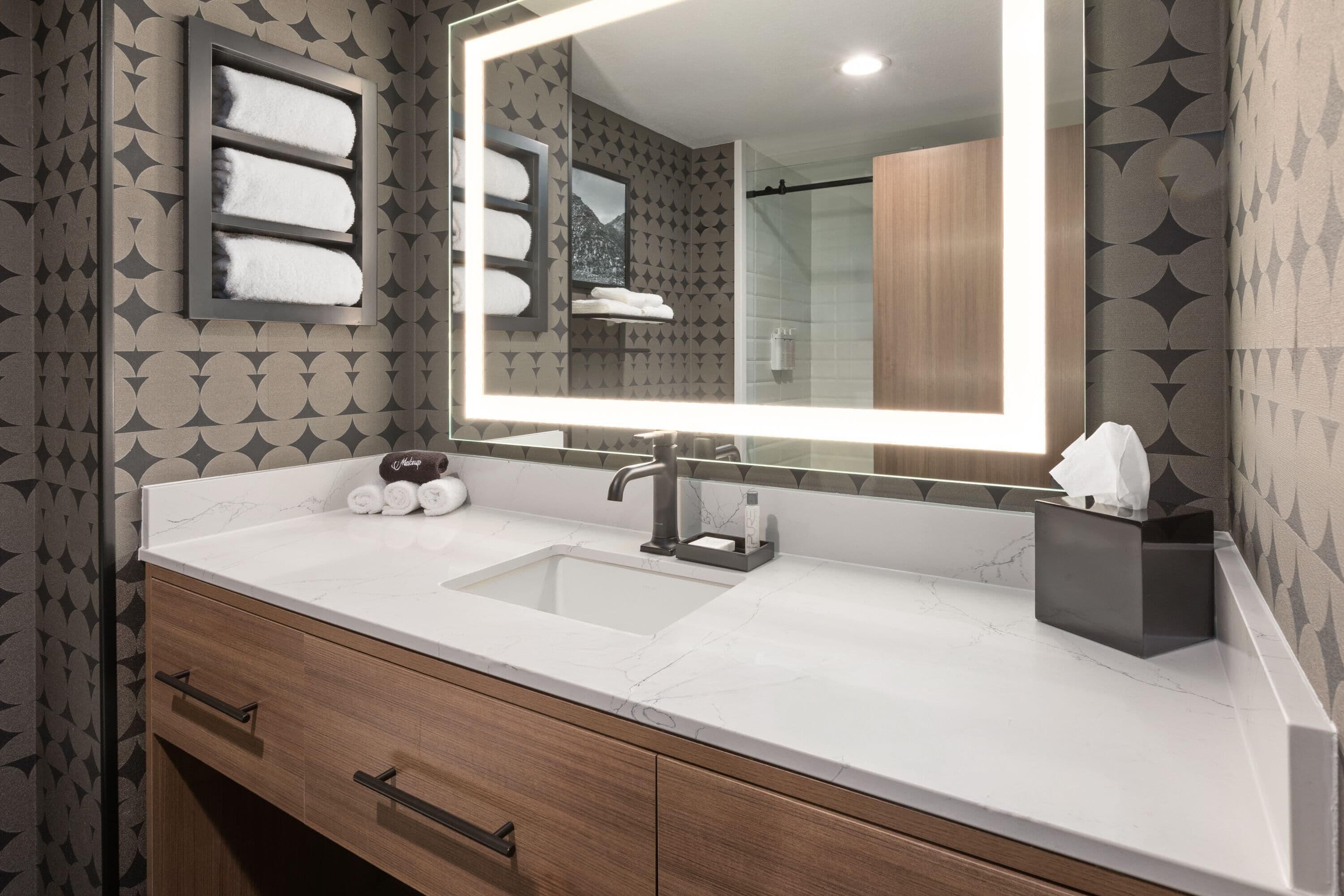 A bathroom with a marble sink, a large mirror, and a towel rack.