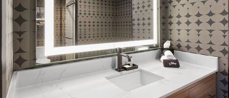 A bathroom with a large mirror, a white marble sink, and a towel holder.