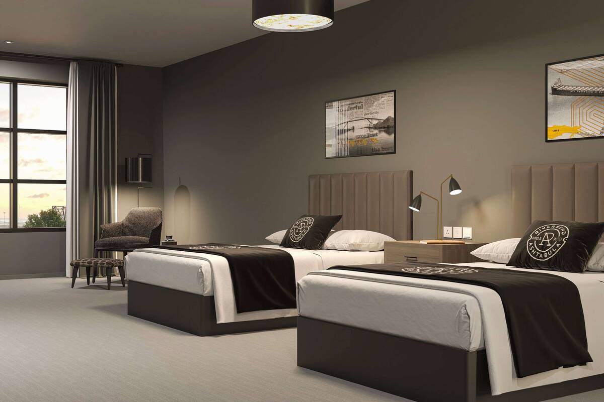 A modern hotel room with two beds, a chair, a desk, and a large window.