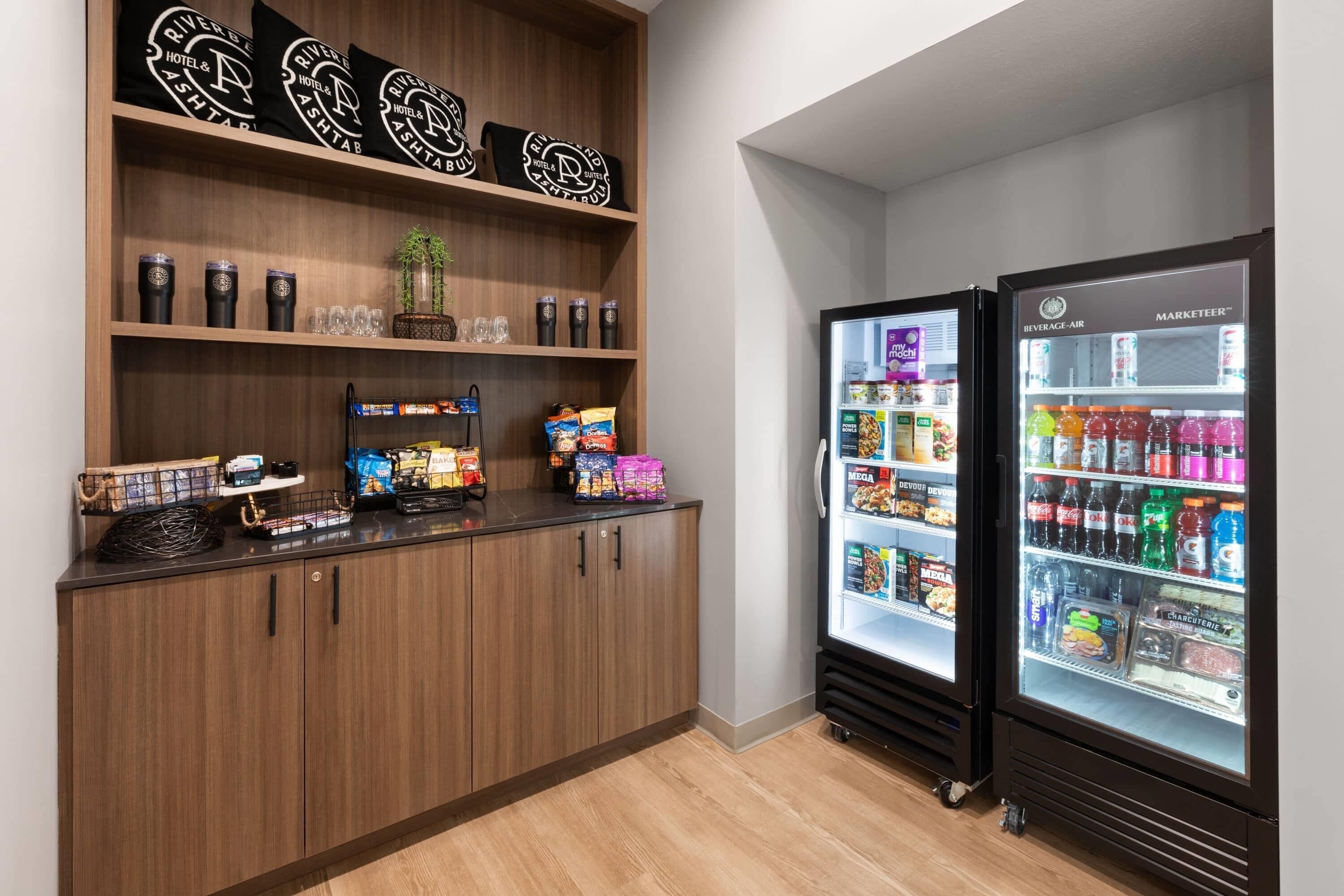 A kitchenette with a wooden cabinet, a coffee machine, and two beverage dispensers.