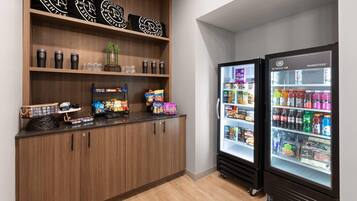 A kitchenette with a wooden cabinet, a coffee machine, and two beverage dispensers.
