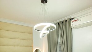 Een moderne slaapkamer met een groot bed, een hanglamp, een spiegel en een raam met gordijnen.