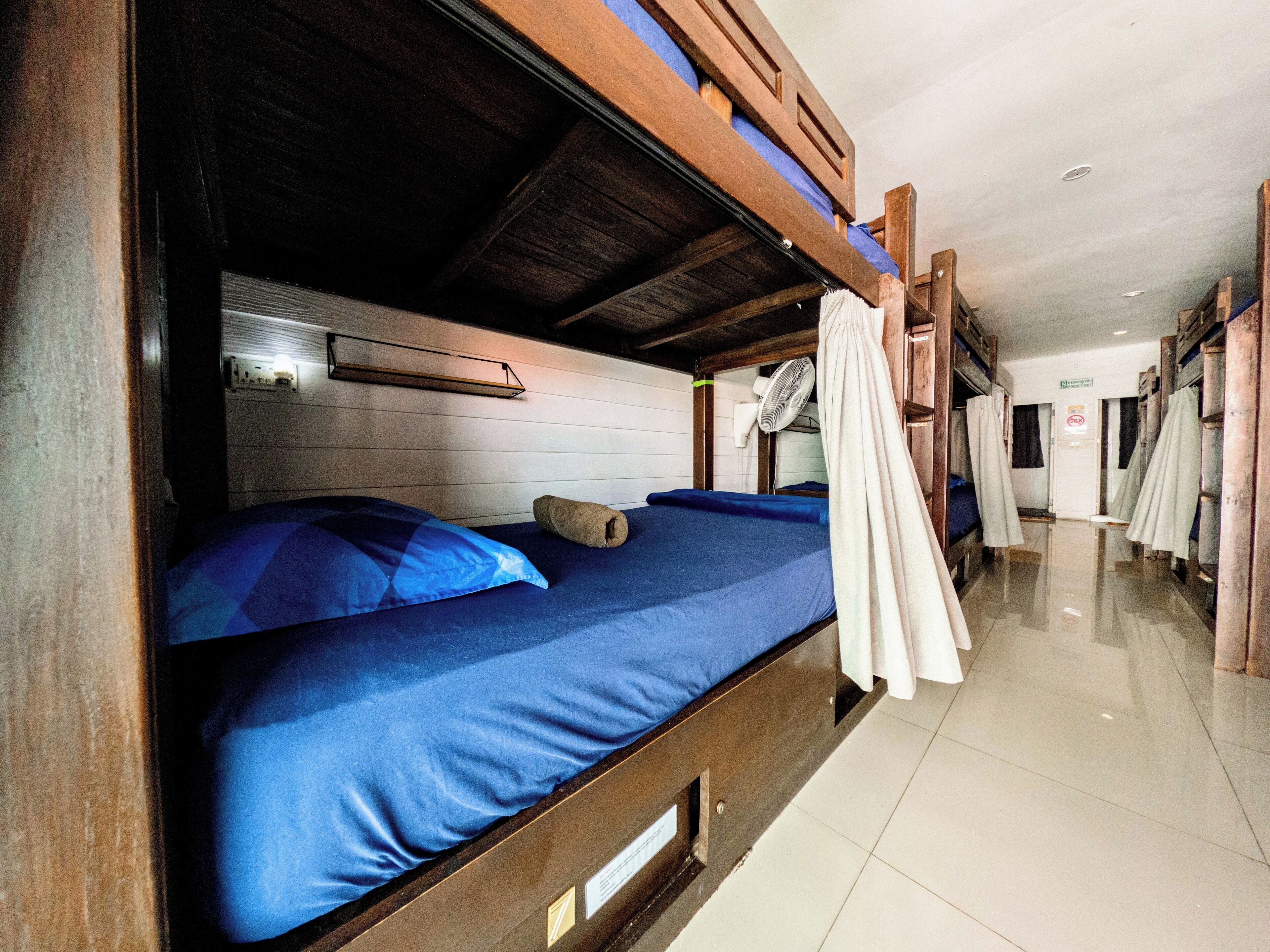 A bunk bed room with a ceiling fan, a visible door, and a tiled floor.