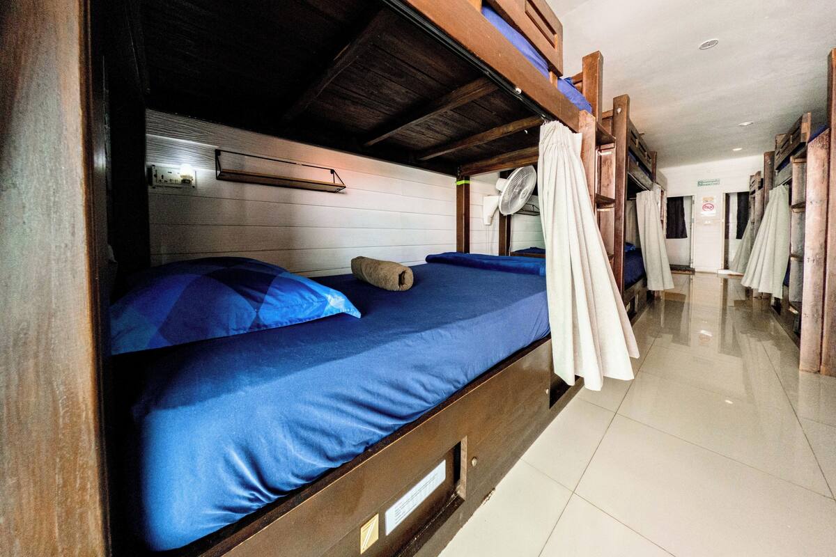 A bunk bed room with a ceiling fan, a visible door, and a tiled floor.