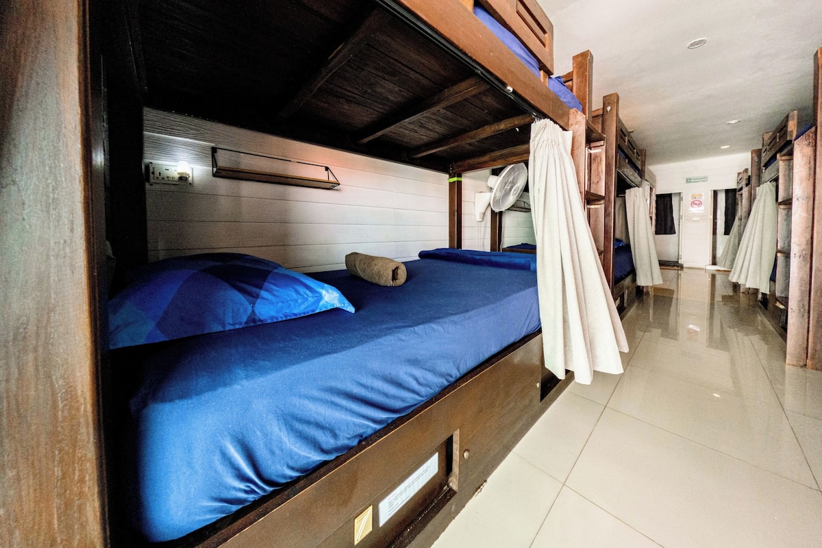 A bunk bed room with a ceiling fan, a visible door, and a tiled floor.