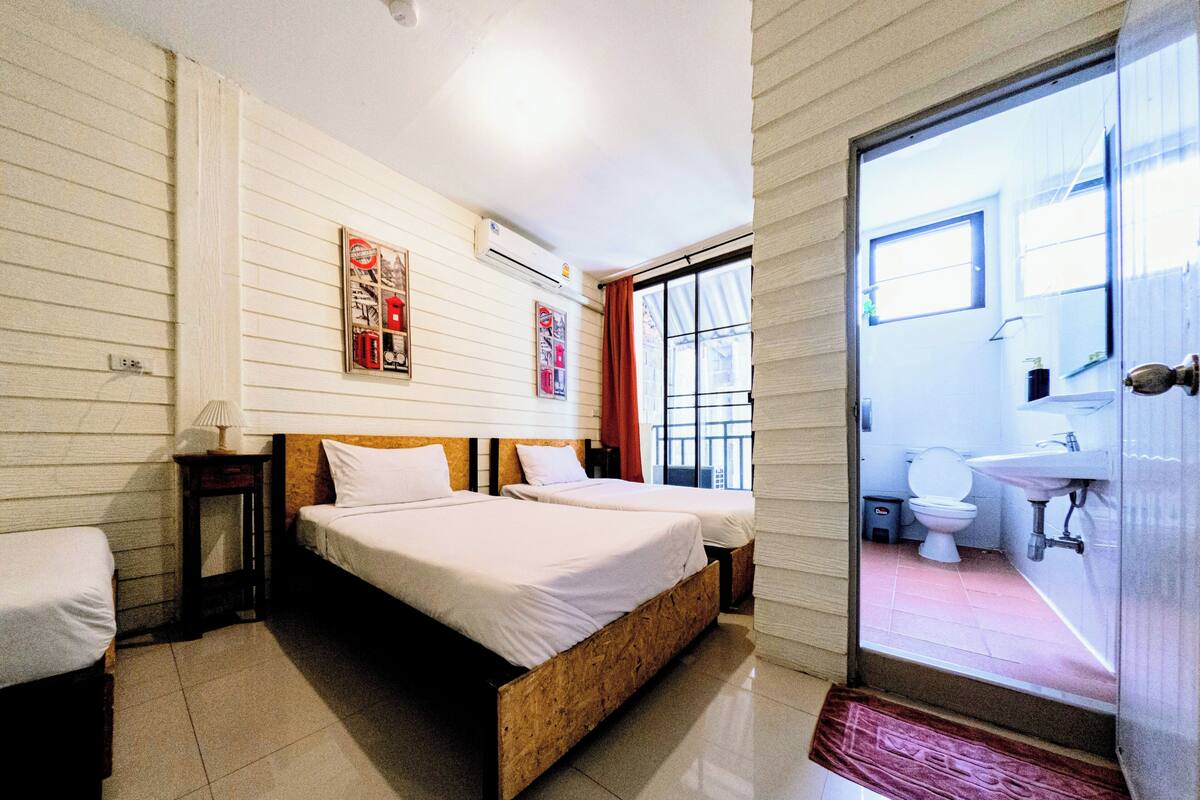 A bedroom with two beds, a bathroom with a sink, and a view through a glass door.