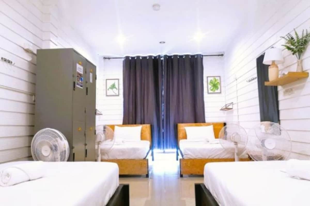 A hotel room with two beds, a wardrobe, a desk, and a large window with curtains.