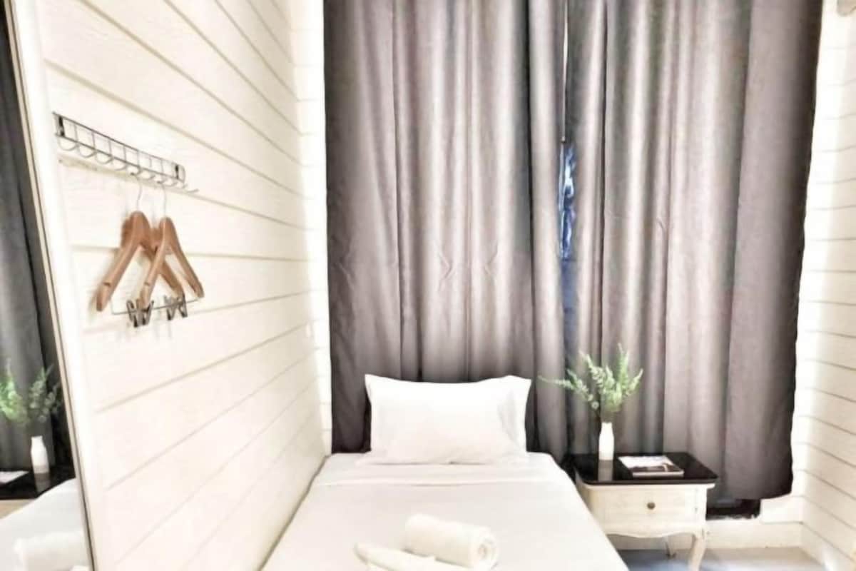 A hotel room with a bed, a nightstand, a mirror, and a window with curtains.