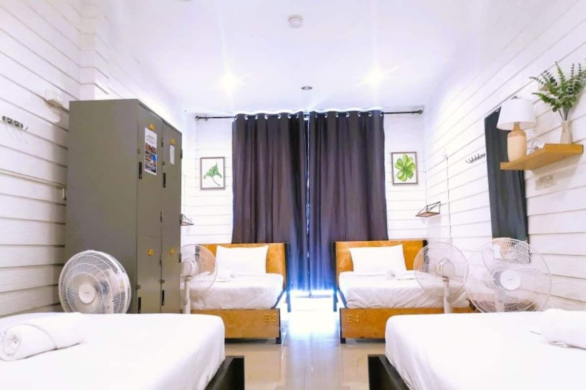 A hotel room with two beds, a wardrobe, a desk, and a window with curtains.