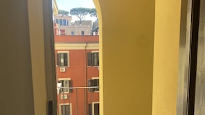 Un couloir avec un mur jaune et une vue sur un bâtiment rouge doté de nombreuses fenêtres et volets.