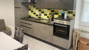 Une cuisine de taille réduite, équipée d’une cuisinière à gaz, d’un four et d’un crédence à carreaux.