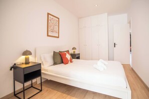 Une chambre à coucher bien rangée, avec un lit, des tables de chevet, une armoire et un tableau encadré au mur.