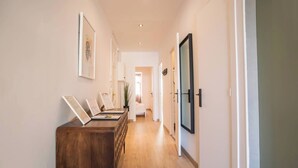 A hallway with a wooden bench, framed artwork on the walls, and a door with a black handle. - 22CRC1039 Exquisite Apartment near the City Center (Barcelona)