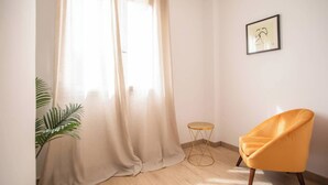A room with a yellow chair, a small round table, a potted plant, and a framed picture on the wall. - 22CRC1039 Exquisite Apartment near the City Center (Barcelona)
