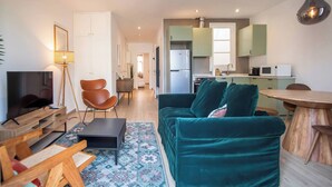 A modern living room with a sofa, TV, and a dining area with a table. - 22CRC1039 Exquisite Apartment near the City Center (Barcelona)