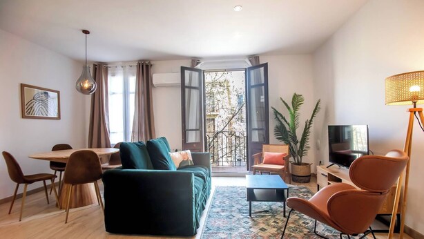 A modern living room with a sofa, chairs, a dining table, and a TV. - 22CRC1039 Exquisite Apartment near the City Center (Barcelona)