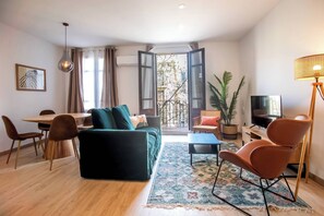 A modern living room with a sofa, chairs, a dining table, and a TV. - 22CRC1039 Exquisite Apartment near the City Center (Barcelona)