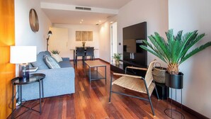 A modern living room with a sofa, a dining table, and a TV.