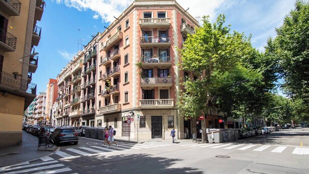A multi-story building with balconies, a pedestrian crossing, and parked cars. - P2VIIV1042  - Modern & Cozy Apartment Poble Sec (Barcelona)