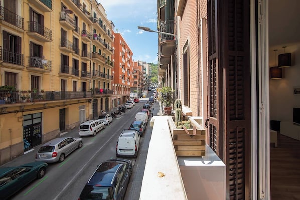 Vista de una calle con edificios de varios pisos, coches aparcados y una acera estrecha.