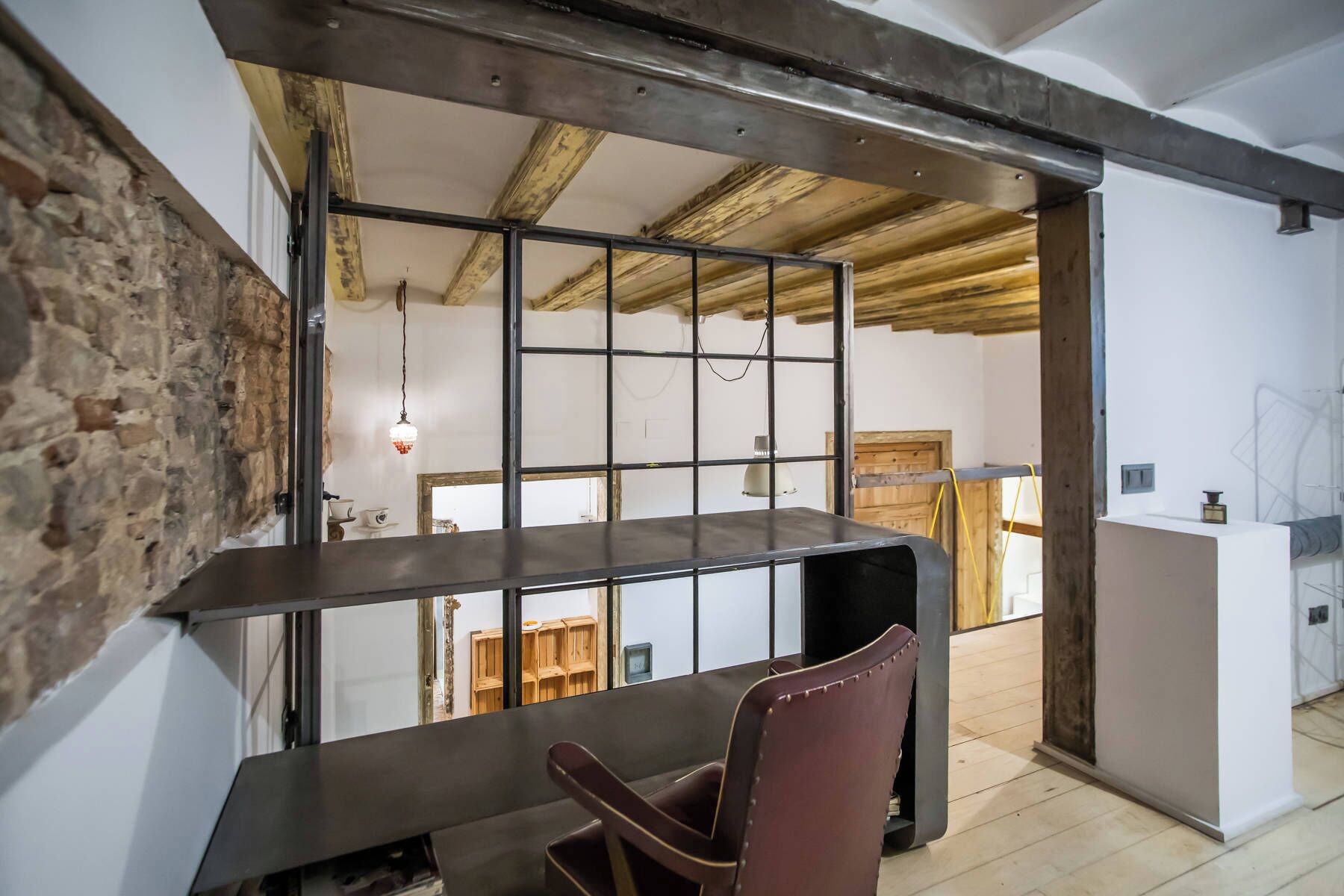 Un interior moderno con techo de madera, ventana de estructura metálica, una mesa de comedor y una silla.