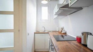 A modern kitchen with a wooden countertop, stainless steel appliances, and a window above the sink.