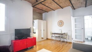 A modern living room with a red entertainment unit, a dining table with chairs, and a large mirror on the wall.