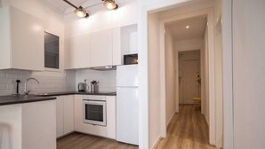 A modern kitchen with white cabinetry, a built-in oven, and a stainless steel sink. - 12par1003- Luminoso piso en Paralelo (Barcelona)