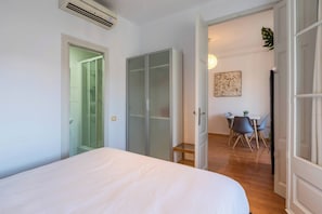 Une chambre comprenant un lit, une armoire, une douche et un coin repas avec des chaises et une table.
