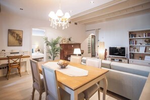 Un salon moderne comprenant un coin repas, un canapé, un téléviseur et une bibliothèque.