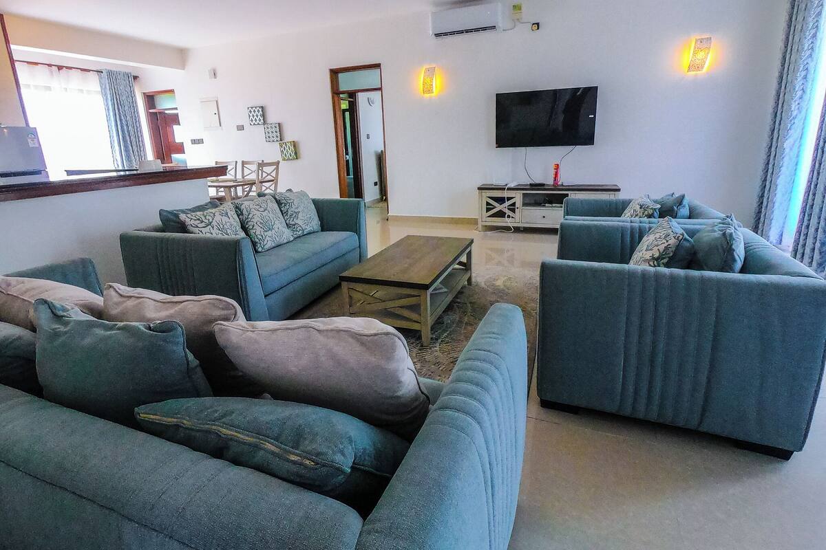 A living room with a sofa set, a coffee table, a TV, and a small cabinet.