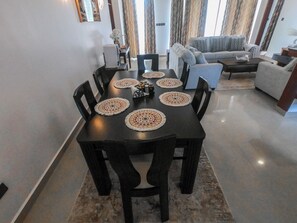 Un coin repas avec une table ronde, des chaises noires et des sets de table décoratifs.