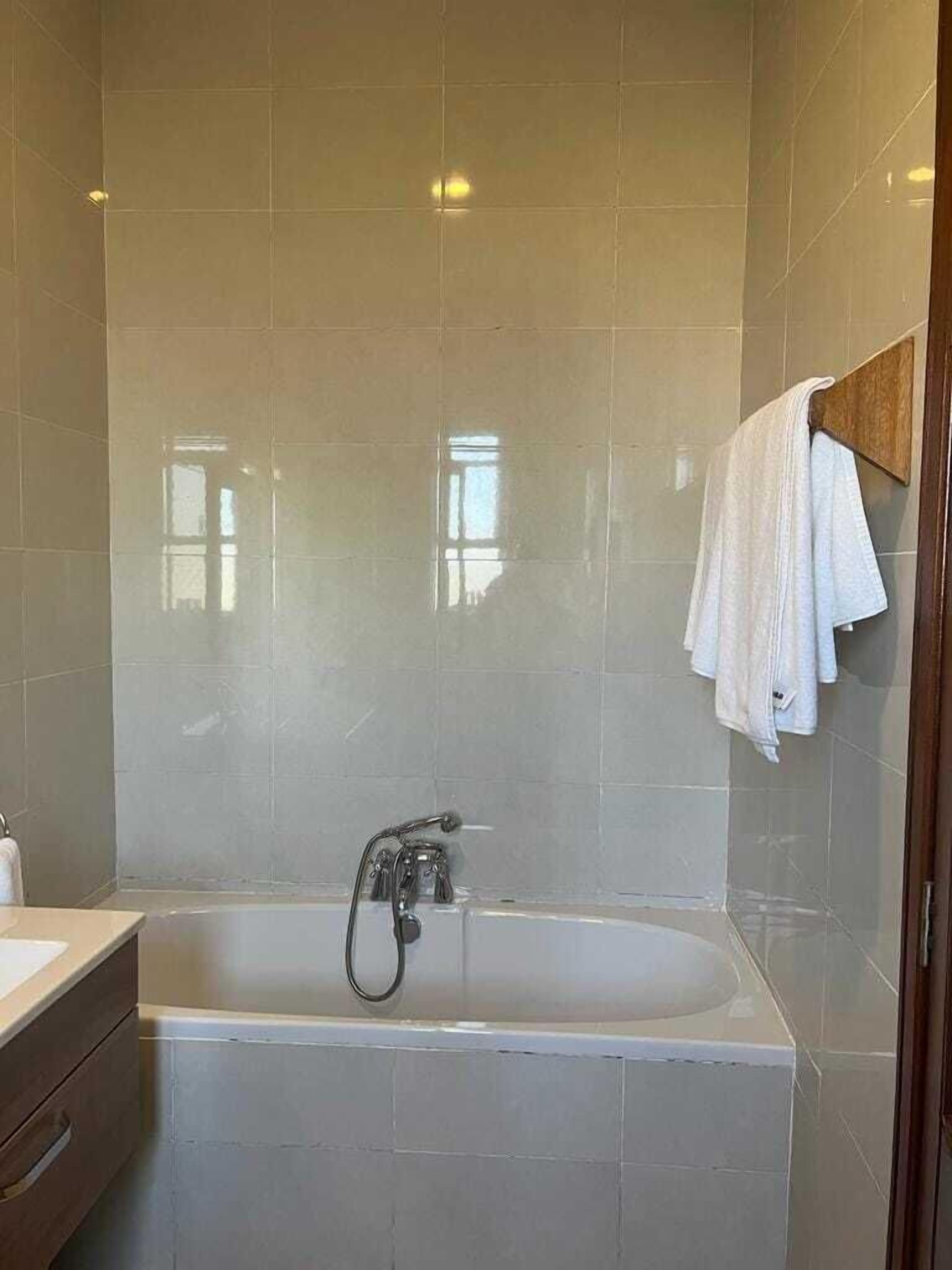 Un baño moderno con bañera, lavamanos y un toallero de madera.