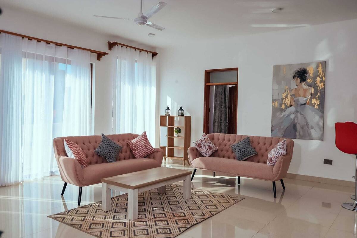 A modern living room with two sofas, a coffee table, and a bookshelf.