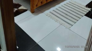 Une chambre d’hôtel avec une tête de lit capitonnée, un lit avec une literie rouge et blanche, un plaid rouge et un tapis à rayures sur le sol.