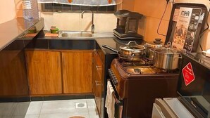 Une cuisine de taille réduite, dotée de meubles de rangement en bois, d’une cuisinière, d’un réfrigérateur et d’un four à micro-ondes.